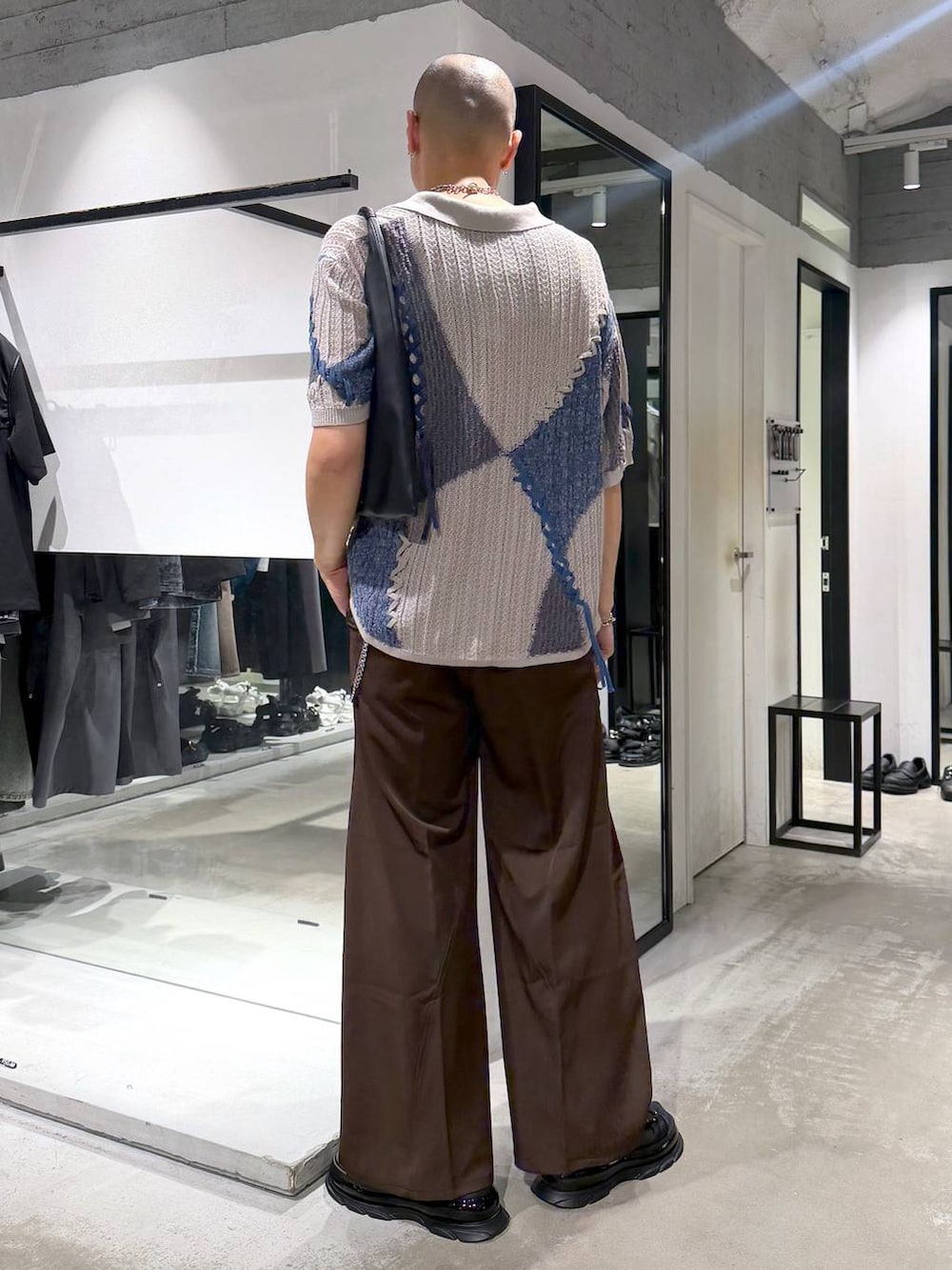 ブラック系のトートバッグ、ブラウン系のスラックス、ブラック系のサンダルを着用したメンズの夏コーディネートの3枚目の写真