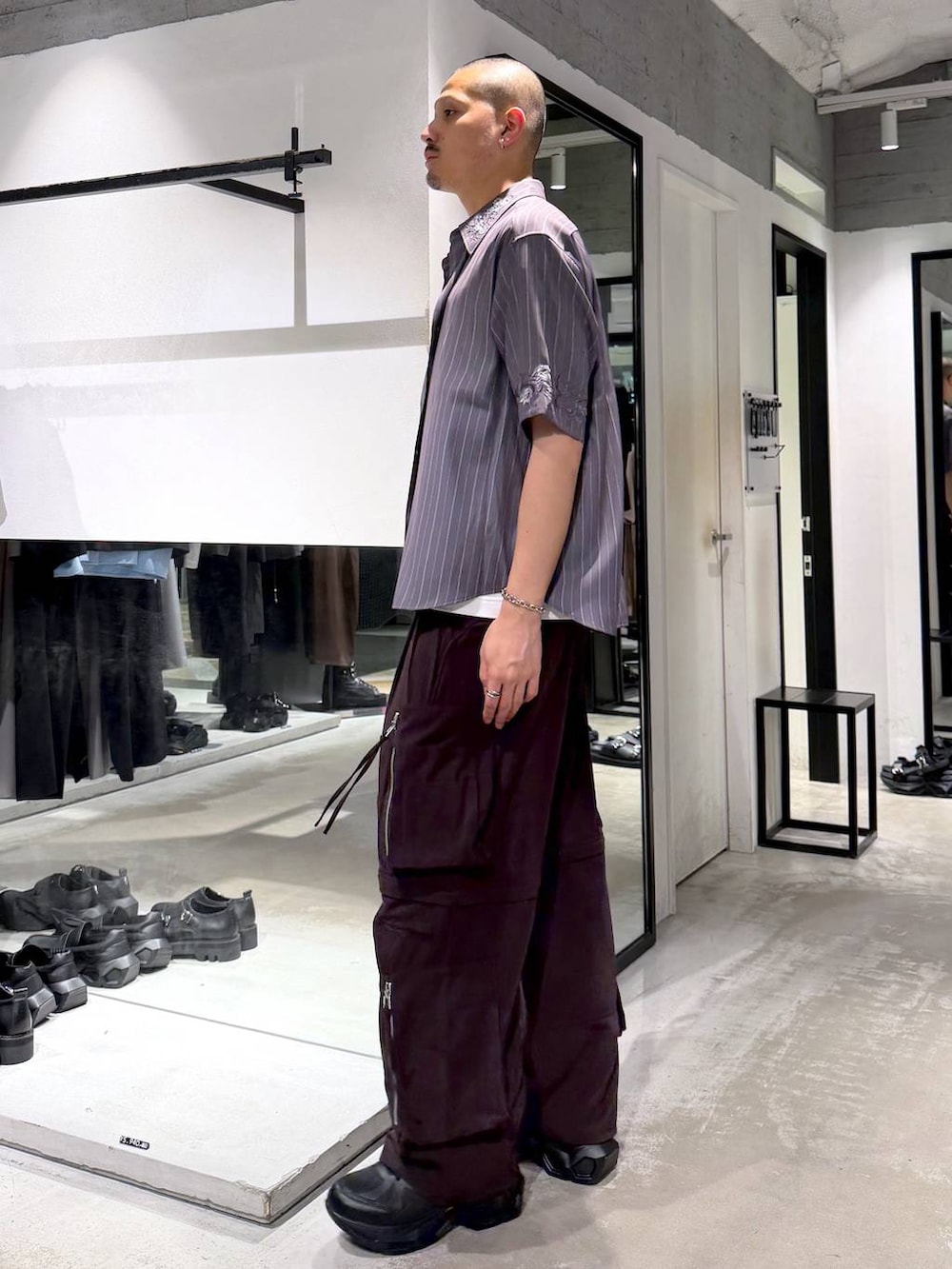 ブラック系のスニーカー、ホワイト系のTシャツ/カットソー、ブラウン系のカーゴパンツを着用したメンズの夏コーディネートの2枚目の写真