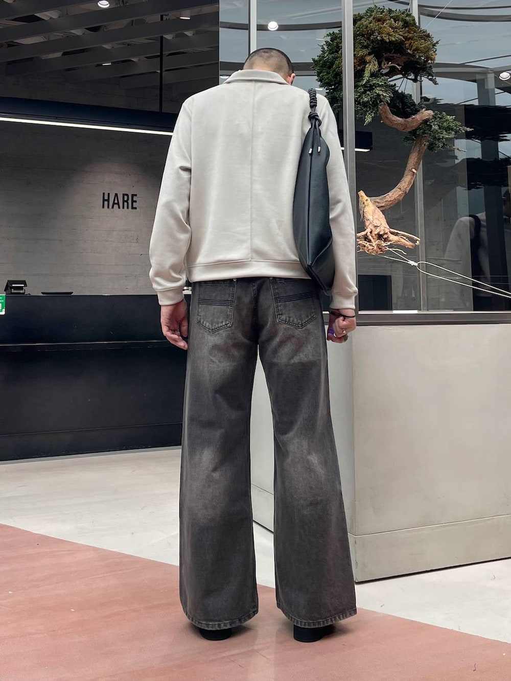 ブラック系のローファー、ブラウン系のデニムパンツ、ブラック系のトートバッグを着用したメンズの秋コーディネートの3枚目の写真