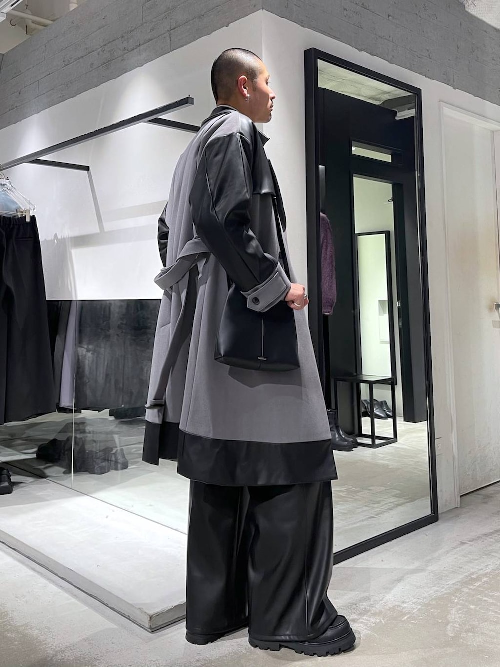 グレー系のトレンチコート、グリーン系のカーディガン/ボレロ、ブラック系のスラックスを着用したメンズの冬コーディネートの4枚目の写真