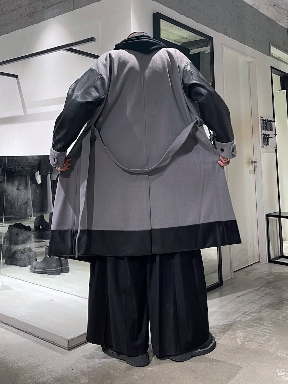 グレー系のトレンチコート、ブラック系のブーツ、ブラック系のスラックスを着用したメンズの秋コーディネートの3枚目の写真