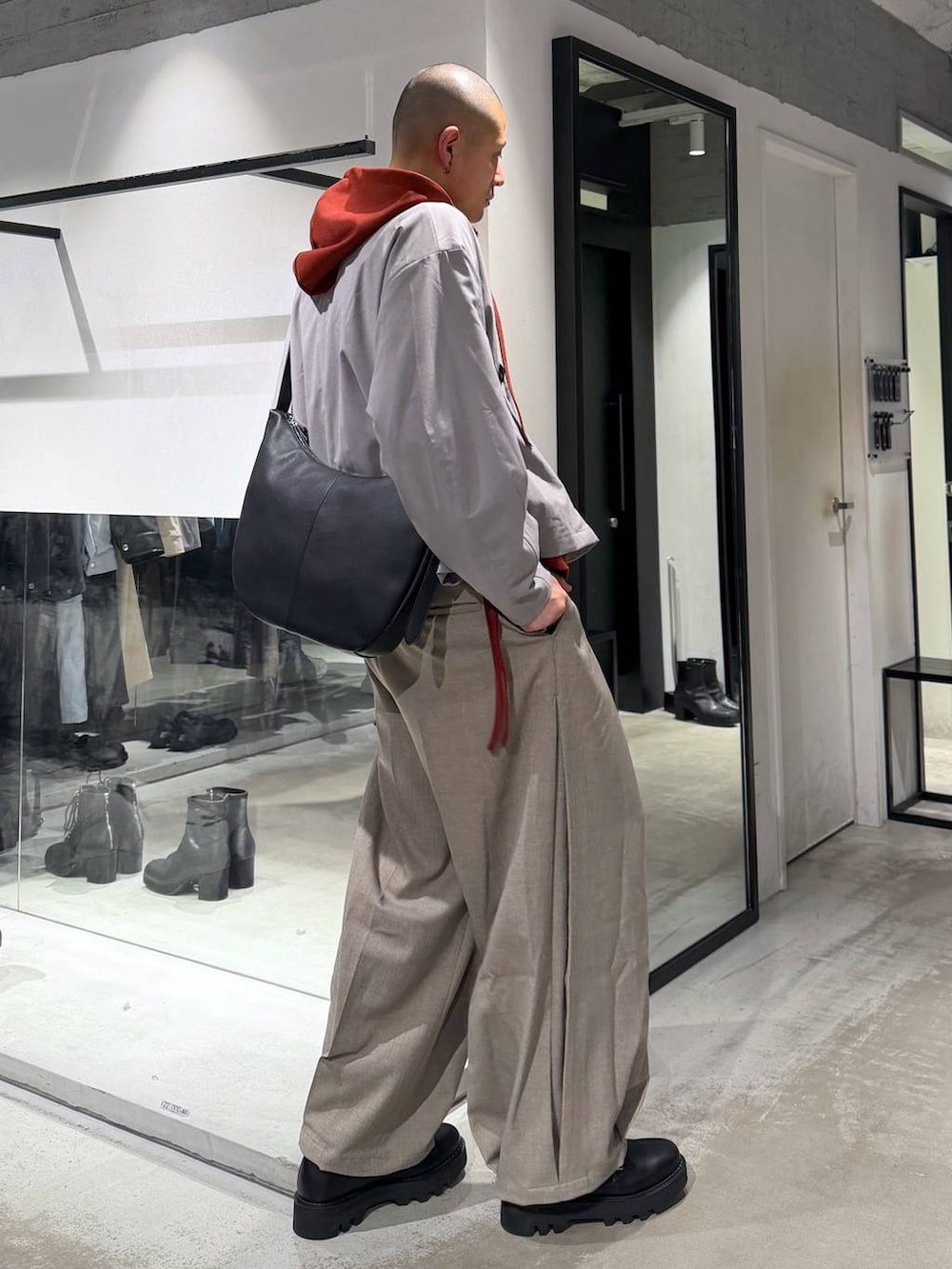 オレンジ系のパーカー、ブラック系のドレスシューズ、ブラック系のショルダーバッグを着用したメンズの春コーディネートの4枚目の写真