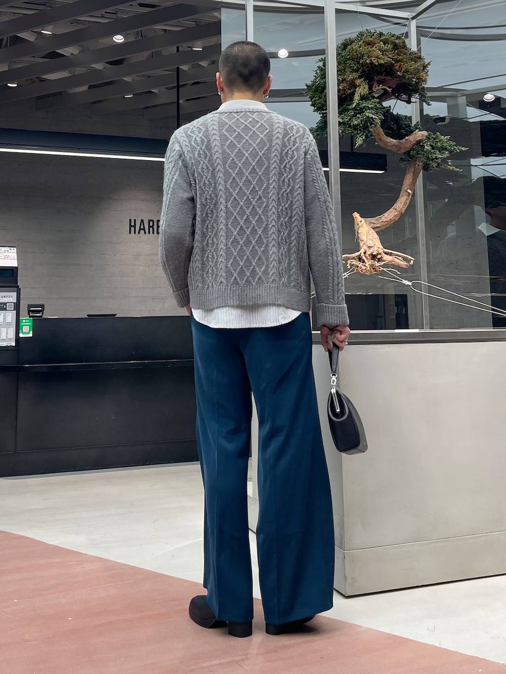 ブルー系のスラックス、ブラック系のショルダーバッグ、ブラック系のブーツを着用したメンズの秋コーディネートの3枚目の写真