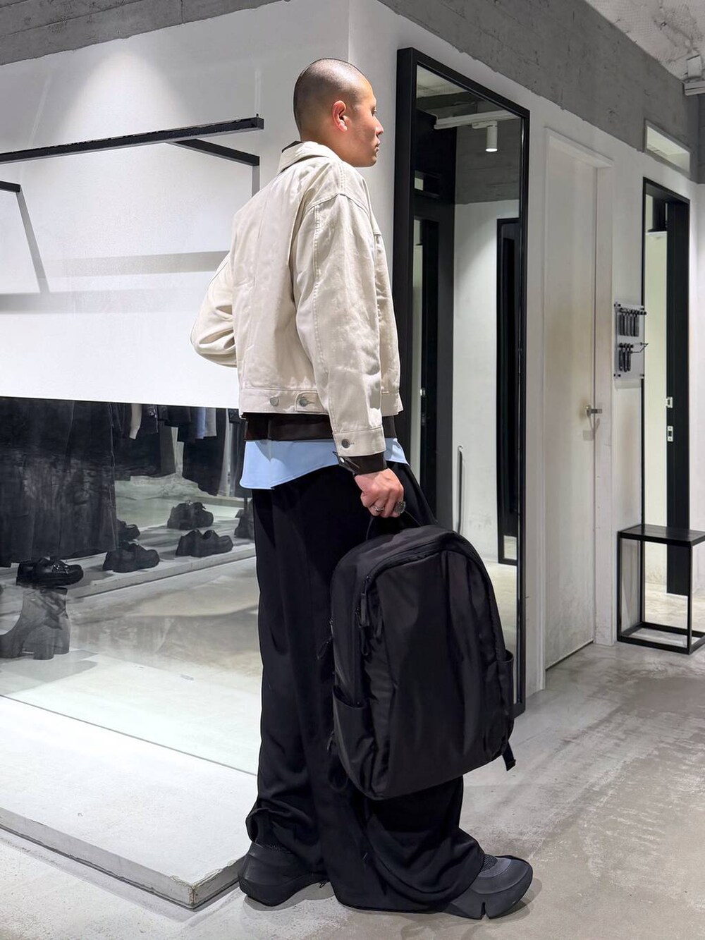 ホワイト系のデニムジャケット、ブラック系のバックパック/リュック、ブラック系のカーゴパンツを着用したメンズの春コーディネートの4枚目の写真