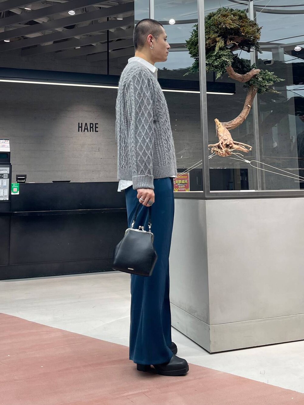 ブルー系のスラックス、ブラック系のショルダーバッグ、ブラック系のブーツを着用したメンズの秋コーディネートの4枚目の写真