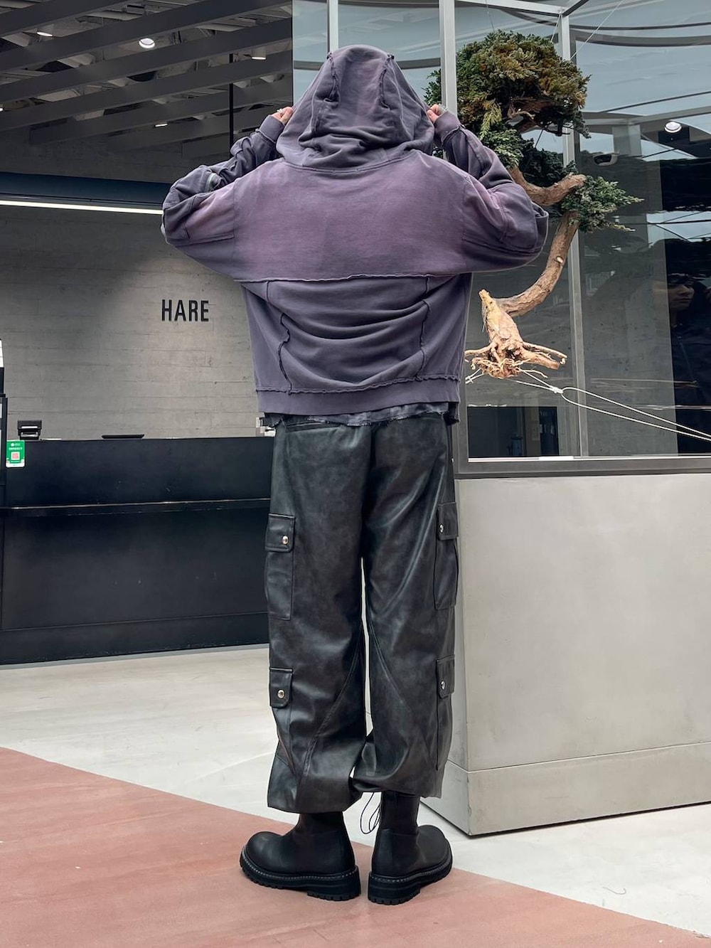 グレー系のカーゴパンツ、パープル系のパーカー、ブラック系のブーツを着用したメンズの秋コーディネートの3枚目の写真