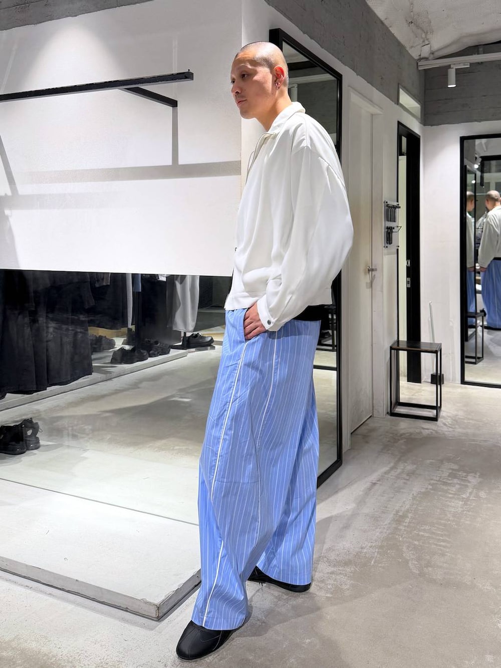 ホワイト系のブルゾン、ブルー系のスラックス、ブラック系のニット/セーターを着用したメンズの春コーディネートの2枚目の写真