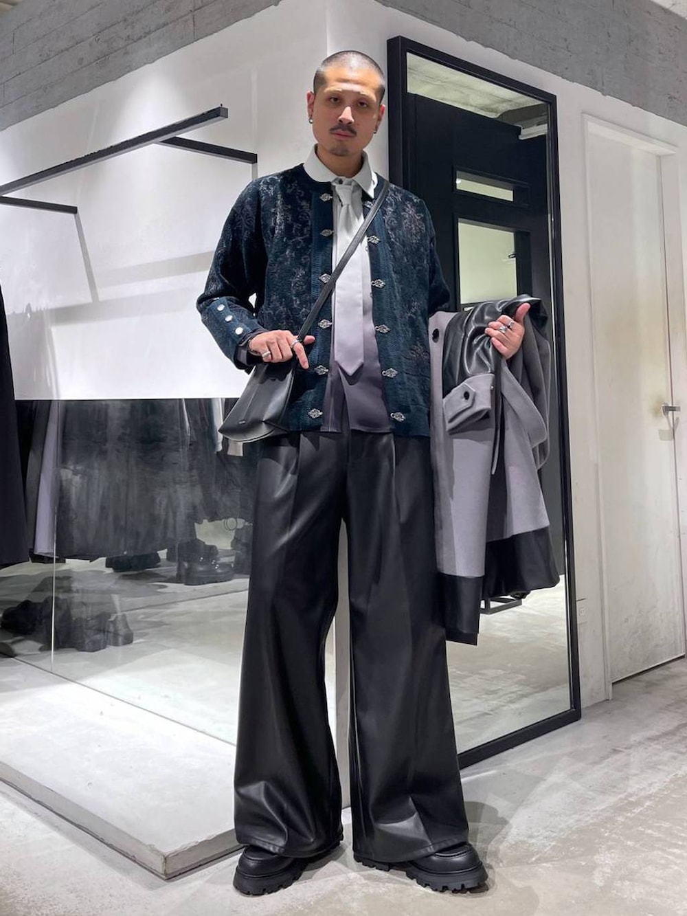 グレー系のトレンチコート、グリーン系のカーディガン/ボレロ、ブラック系のスラックスを着用したメンズの冬コーディネートの5枚目の写真