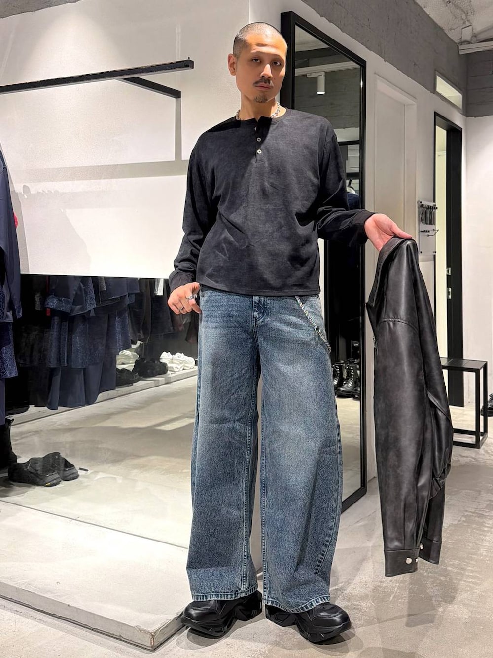 ブルー系のデニムパンツ、ブラック系のTシャツ/カットソー、ブラック系のスニーカーを着用したメンズの秋コーディネートの5枚目の写真