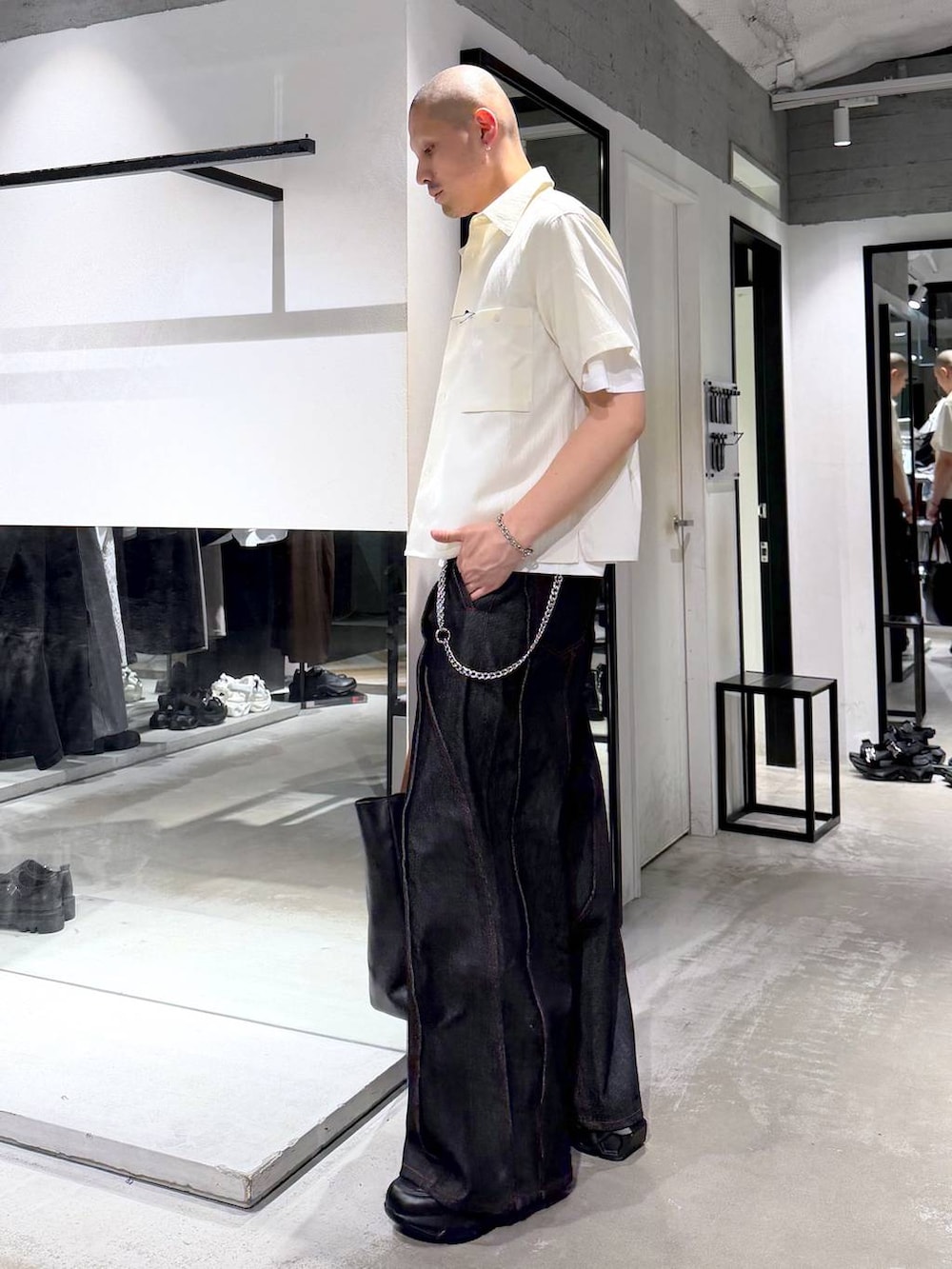 ブラック系のデニムパンツ、ブラック系のトートバッグ、ホワイト系のシャツ/ブラウスを着用したメンズの夏コーディネートの2枚目の写真