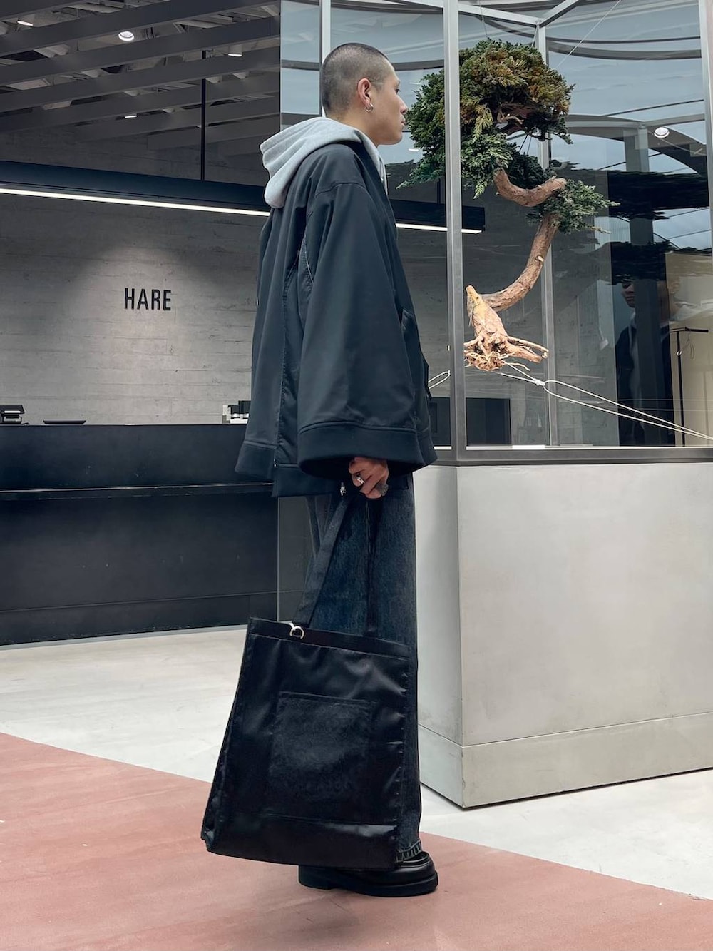 グレー系のパーカー、ブラック系のトートバッグ、ブラック系のローファーを着用したメンズの秋コーディネートの5枚目の写真