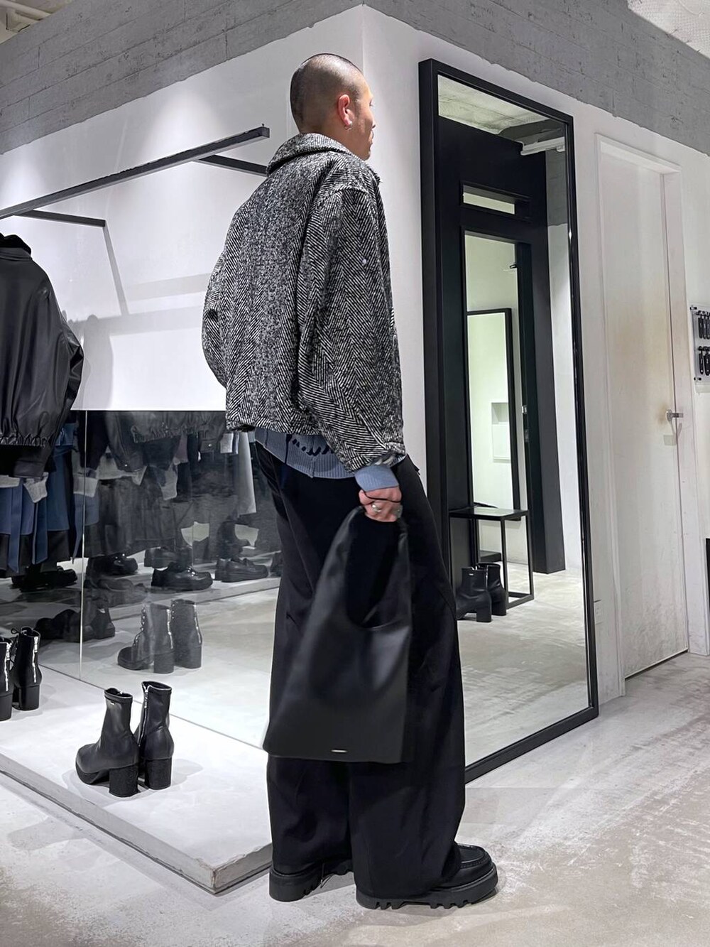 ブラック系のトートバッグ、グレー系のブルゾン、ブラック系のスラックスを着用したメンズの冬コーディネートの4枚目の写真