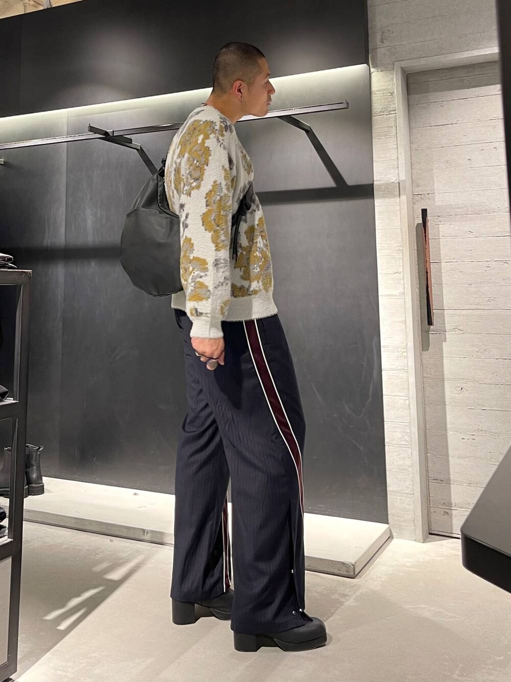 ホワイト系のニット/セーター、ブラック系のブーツ、ブラック系のショルダーバッグを着用したメンズの秋コーディネートの4枚目の写真