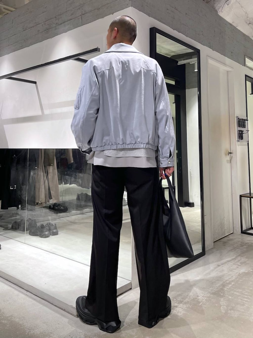 ブラック系のトートバッグ、ブルー系のブルゾン、グレー系のシャツ/ブラウスを着用したメンズの冬コーディネートの3枚目の写真