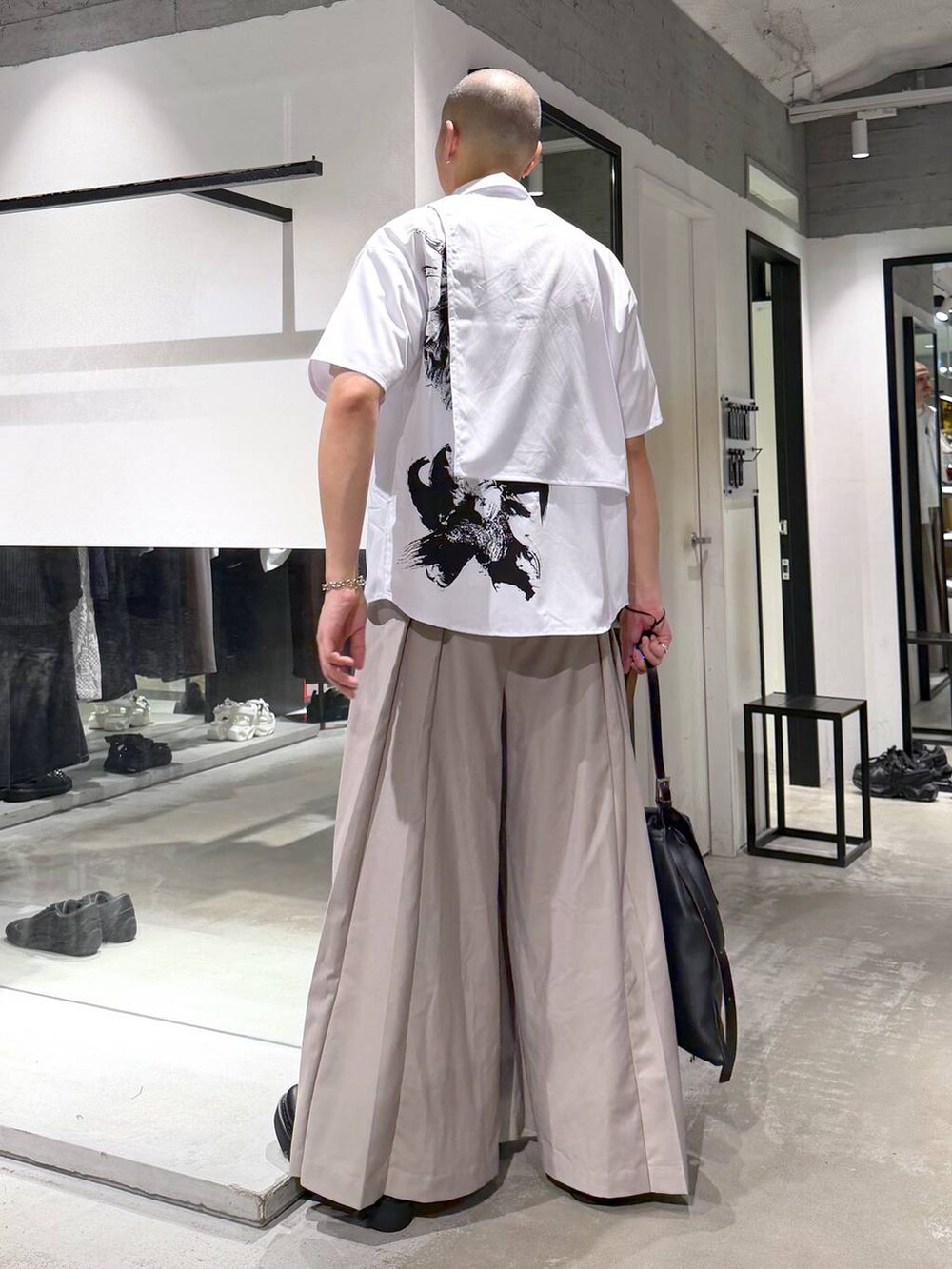 ブラック系のドレスシューズ、ブラック系のトートバッグ、ベージュ系のスラックスを着用したメンズの夏コーディネートの3枚目の写真