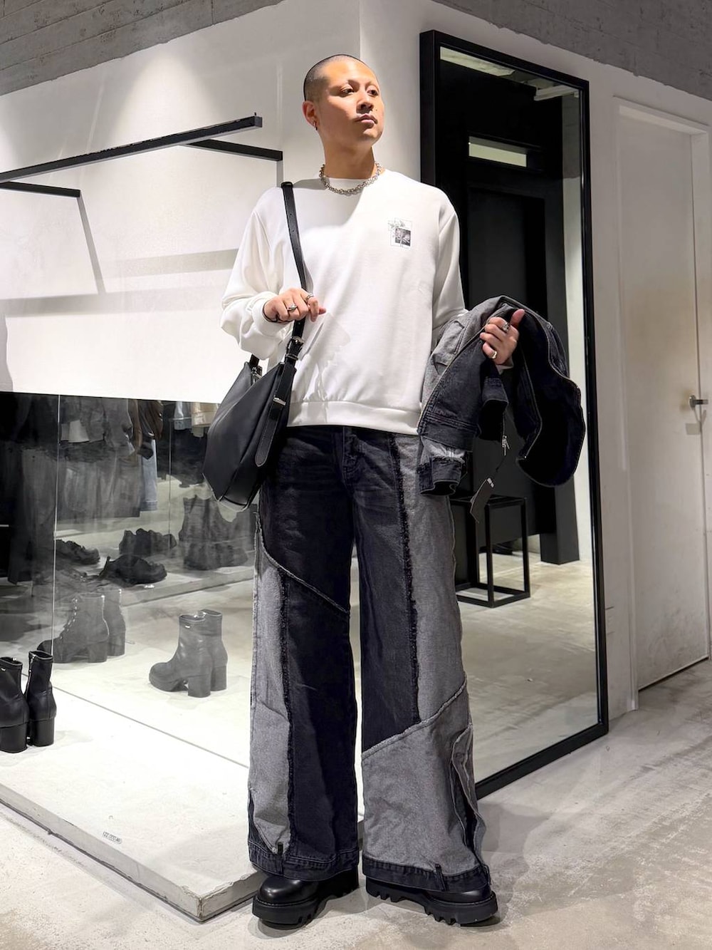 ブラック系のデニムパンツ、ブラック系のドレスシューズ、ブラック系のショルダーバッグを着用したメンズの冬コーディネートの5枚目の写真