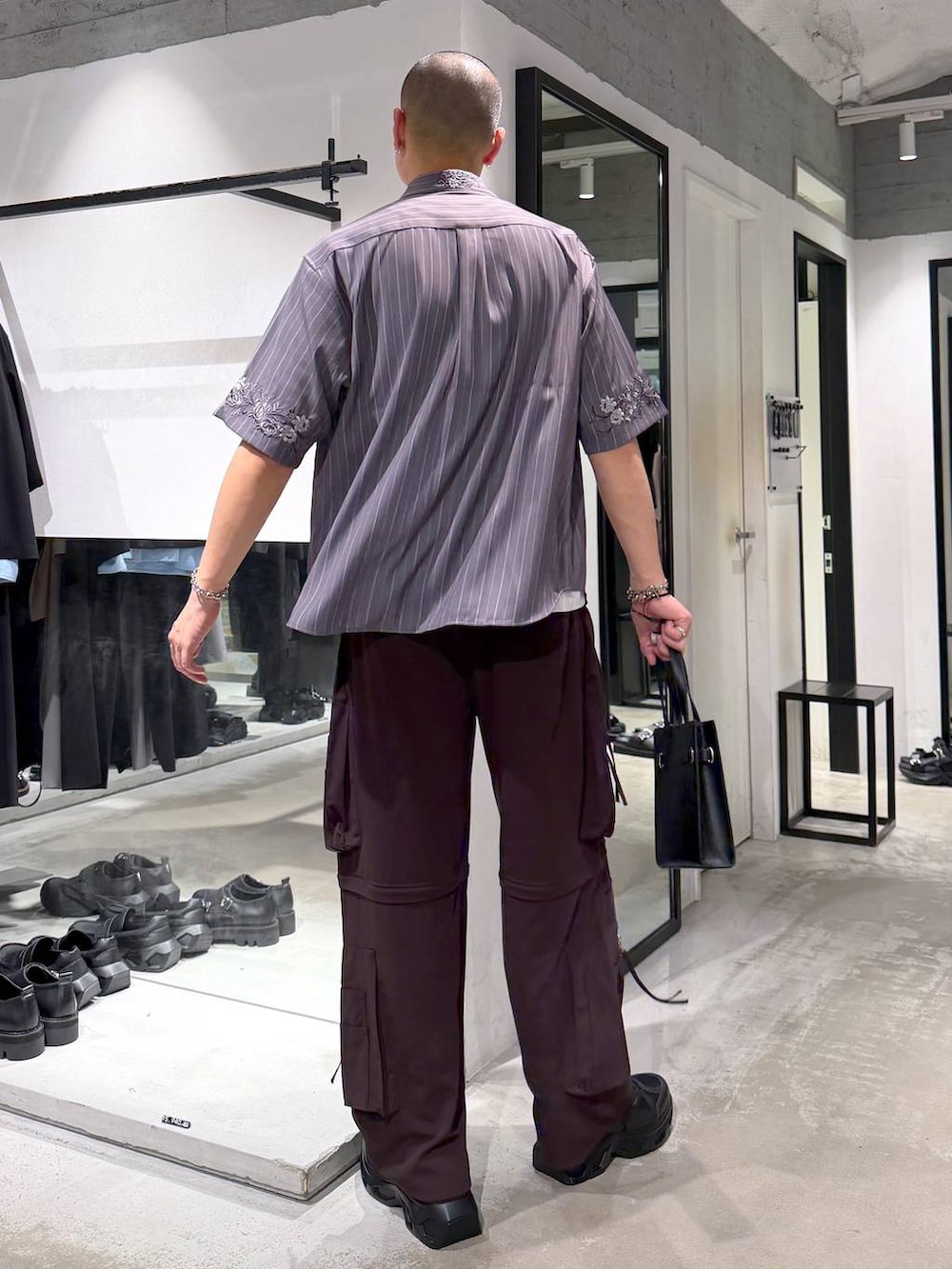ブラック系のスニーカー、ホワイト系のTシャツ/カットソー、ブラウン系のカーゴパンツを着用したメンズの夏コーディネートの3枚目の写真