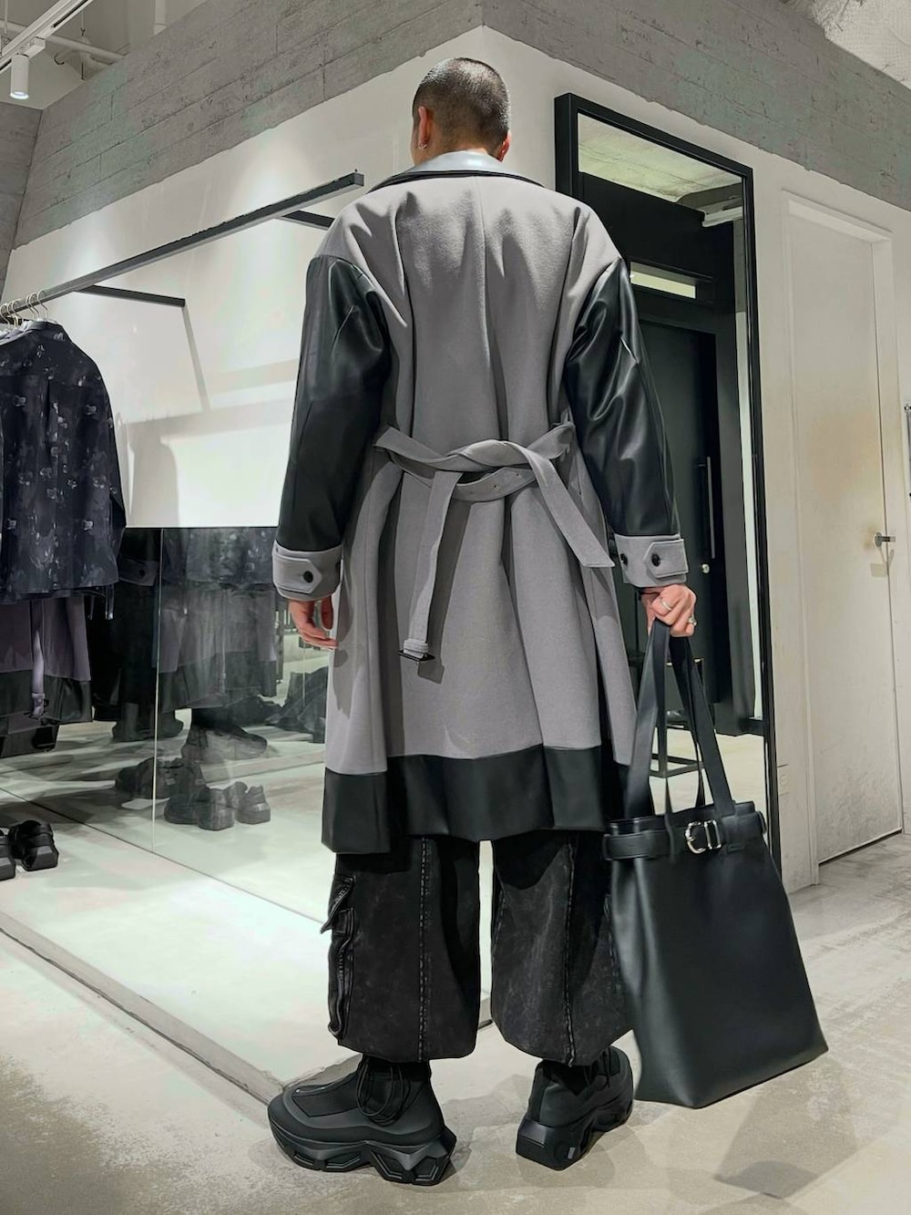 グレー系のトレンチコート、ブルー系のカーディガン/ボレロ、ブラック系のトートバッグを着用したメンズの冬コーディネートの3枚目の写真
