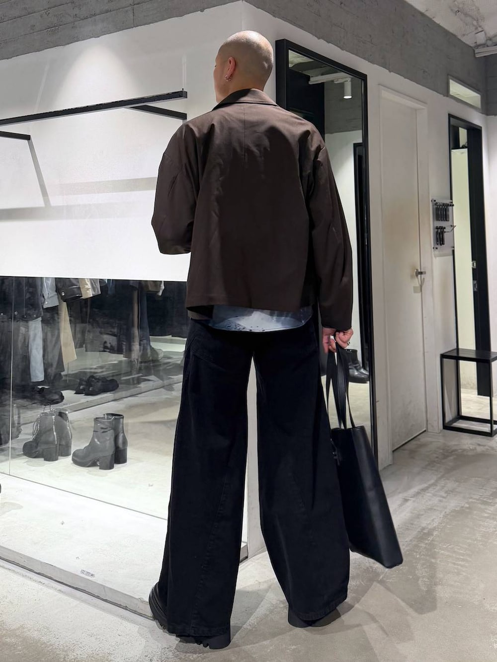 ブラック系のデニムパンツ、ブラック系のドレスシューズ、ブラック系のトートバッグを着用したメンズの冬コーディネートの3枚目の写真