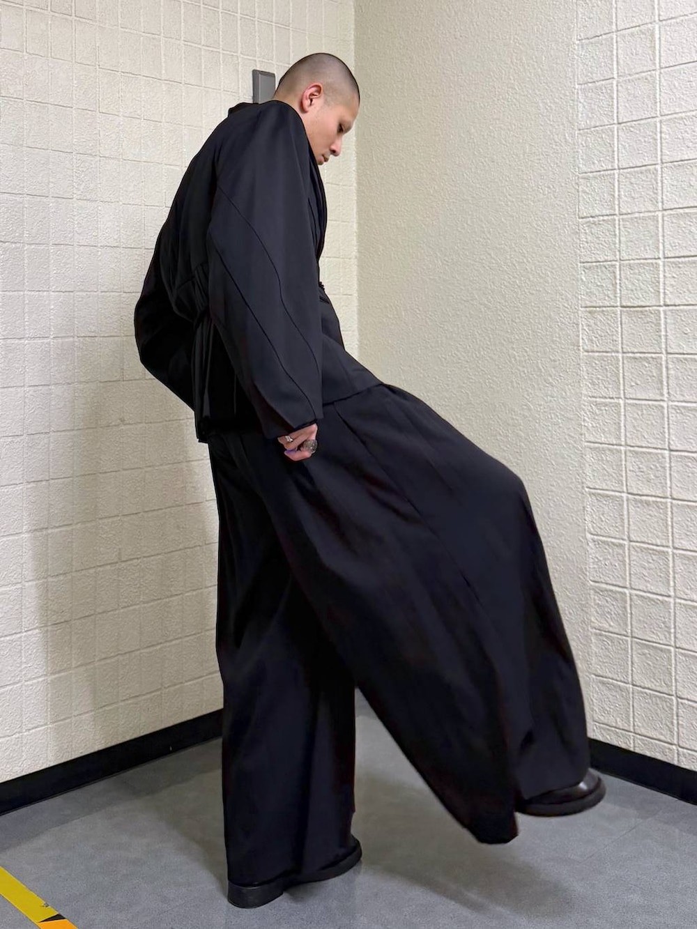 ブラック系のノーカラージャケットを着用したメンズの春コーディネートの5枚目の写真