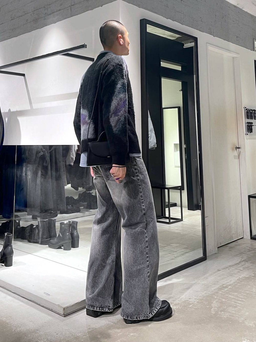 グレー系のデニムパンツ、ブラック系のローファー、ブラック系のショルダーバッグを着用したメンズの冬コーディネートの4枚目の写真