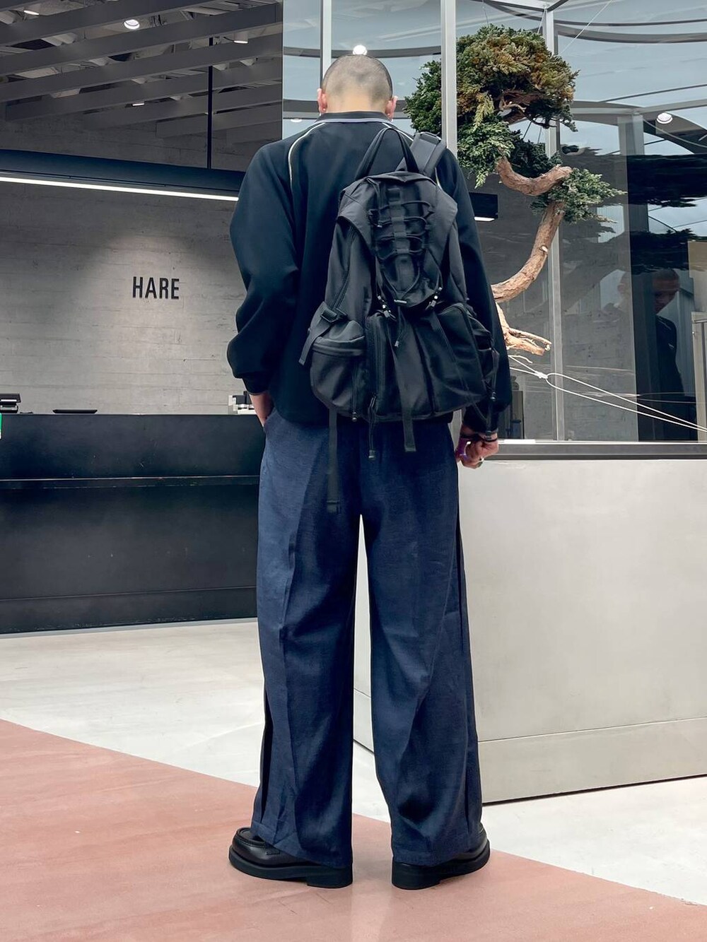 ブルー系のスラックス、ブラック系のローファー、ブラック系のバックパック/リュックを着用したメンズの秋コーディネートの3枚目の写真