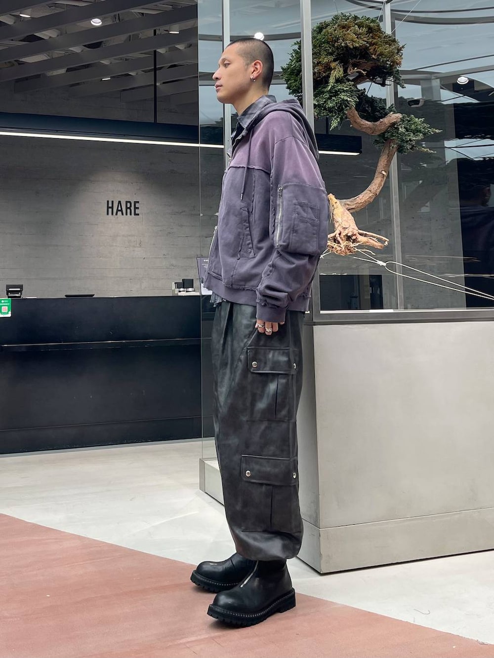 グレー系のカーゴパンツ、パープル系のパーカー、ブラック系のブーツを着用したメンズの秋コーディネートの2枚目の写真