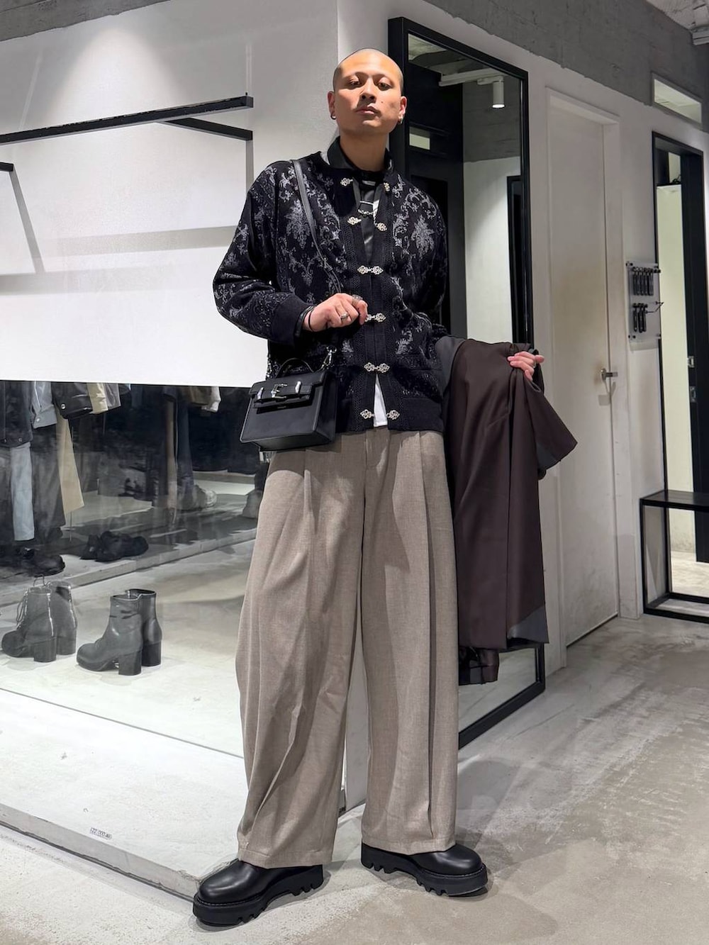 ブラック系のドレスシューズ、ブラック系のハンドバッグ、ブラック系のカーディガン/ボレロを着用したメンズの冬コーディネートの5枚目の写真