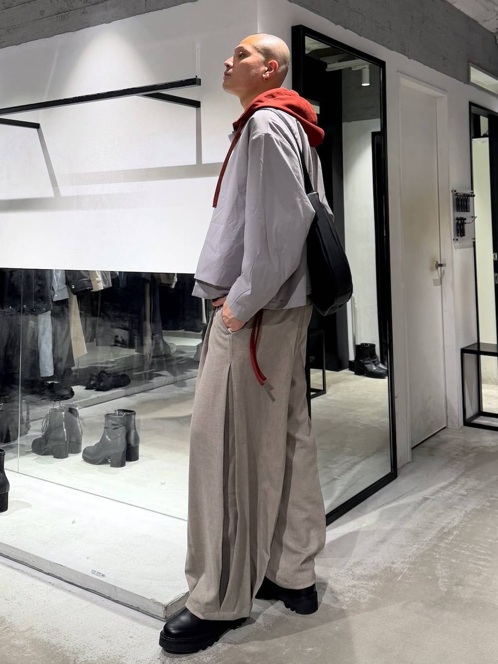 オレンジ系のパーカー、ブラック系のドレスシューズ、ブラック系のショルダーバッグを着用したメンズの春コーディネートの2枚目の写真