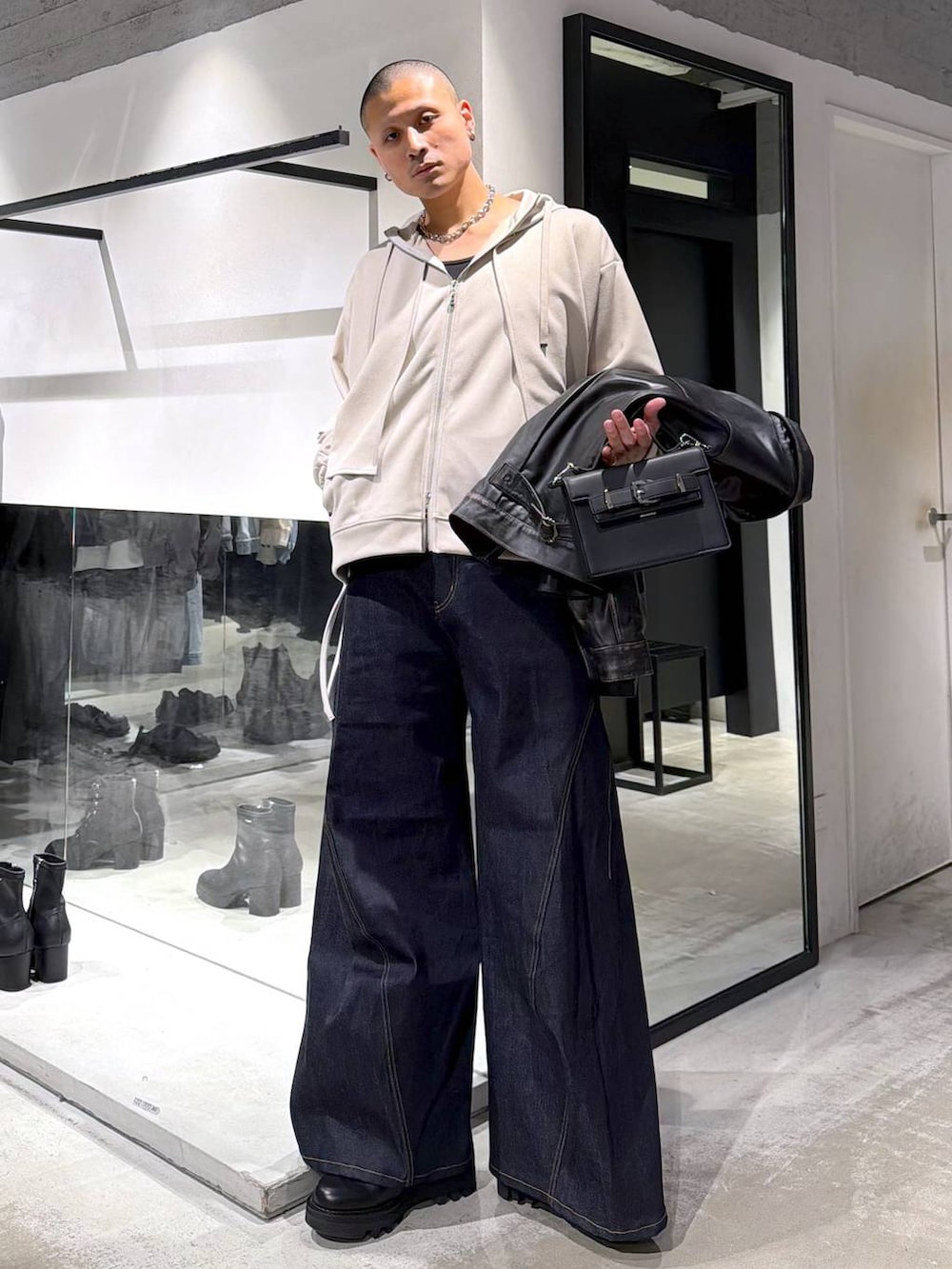 グレー系のパーカー、ブラック系のドレスシューズ、ブラック系のハンドバッグを着用したメンズの冬コーディネートの5枚目の写真