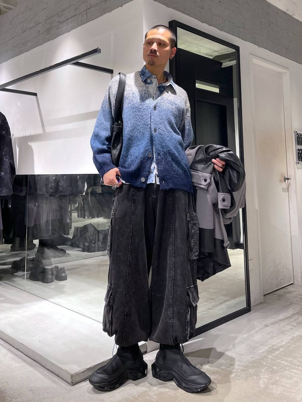 グレー系のトレンチコート、ブルー系のカーディガン/ボレロ、ブラック系のトートバッグを着用したメンズの冬コーディネートの5枚目の写真