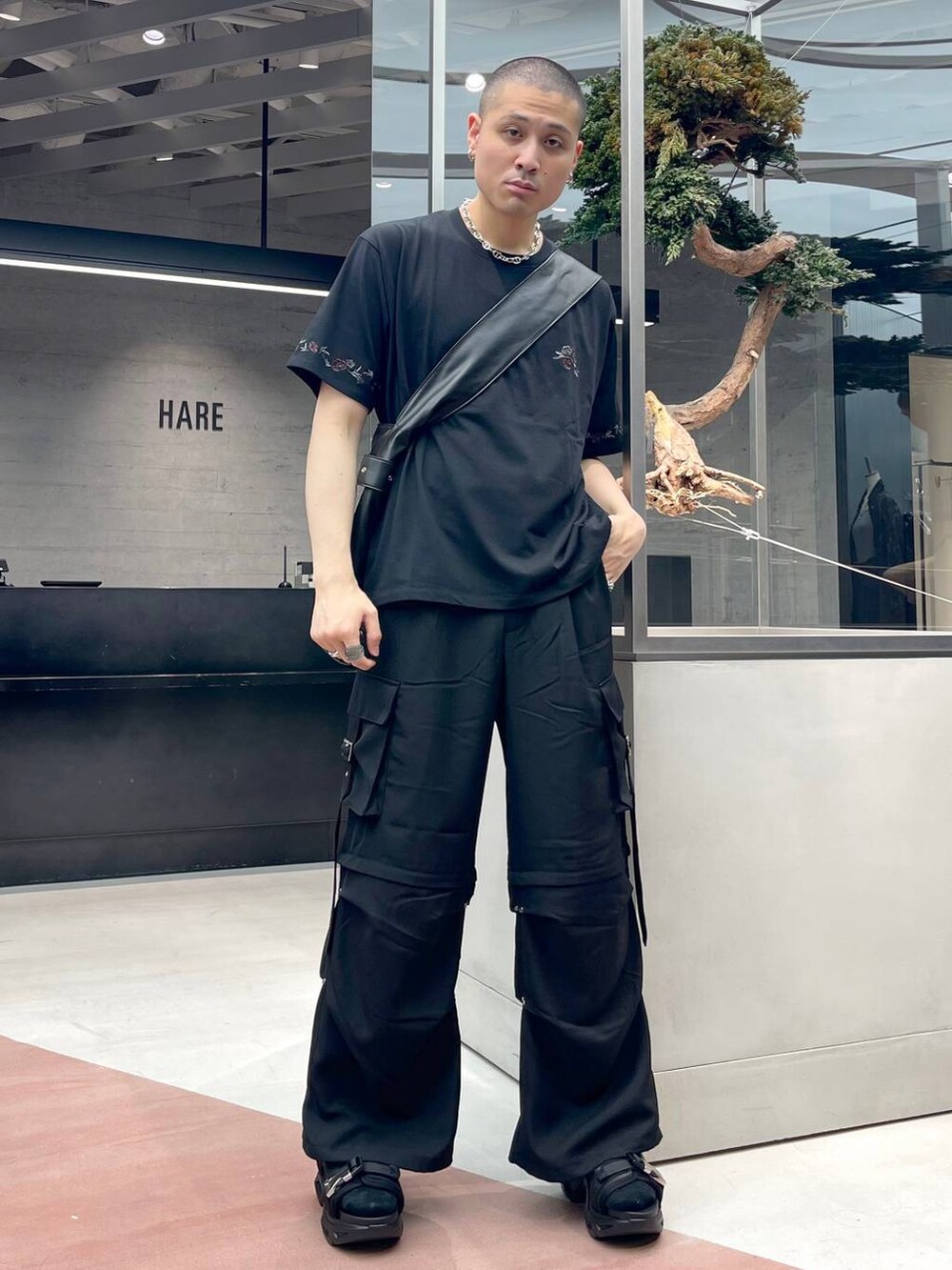 ブラック系のショルダーバッグ、ブラック系のサンダル、ブラック系のカーゴパンツを着用したメンズの夏コーディネートの2枚目の写真