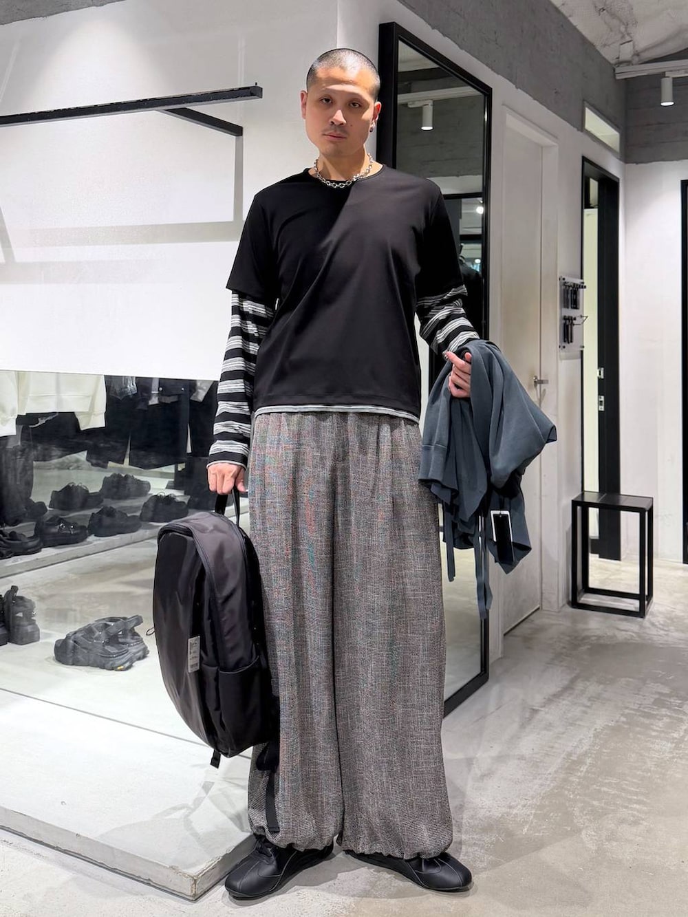 ブラック系のバックパック/リュック、グレー系のスラックス、グリーン系のカーディガン/ボレロを着用したメンズの春コーディネートの7枚目の写真