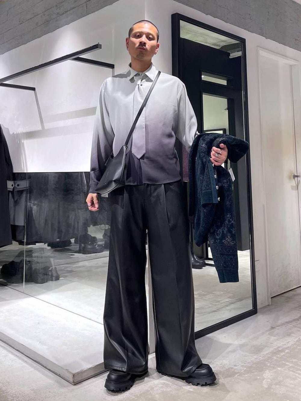 グレー系のトレンチコート、グリーン系のカーディガン/ボレロ、ブラック系のスラックスを着用したメンズの冬コーディネートの6枚目の写真