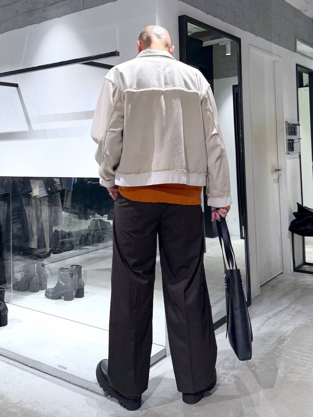 ブラック系のドレスシューズ、ブラック系のトートバッグ、オレンジ系のニット/セーターを着用したメンズの冬コーディネートの3枚目の写真