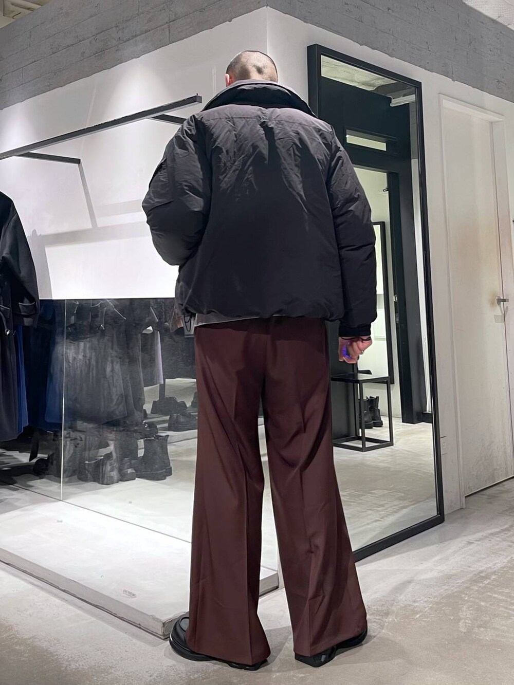 グレー系のニット/セーター、ブラック系のダウンジャケット/コート、レッド系のスラックスを着用したメンズの冬コーディネートの3枚目の写真