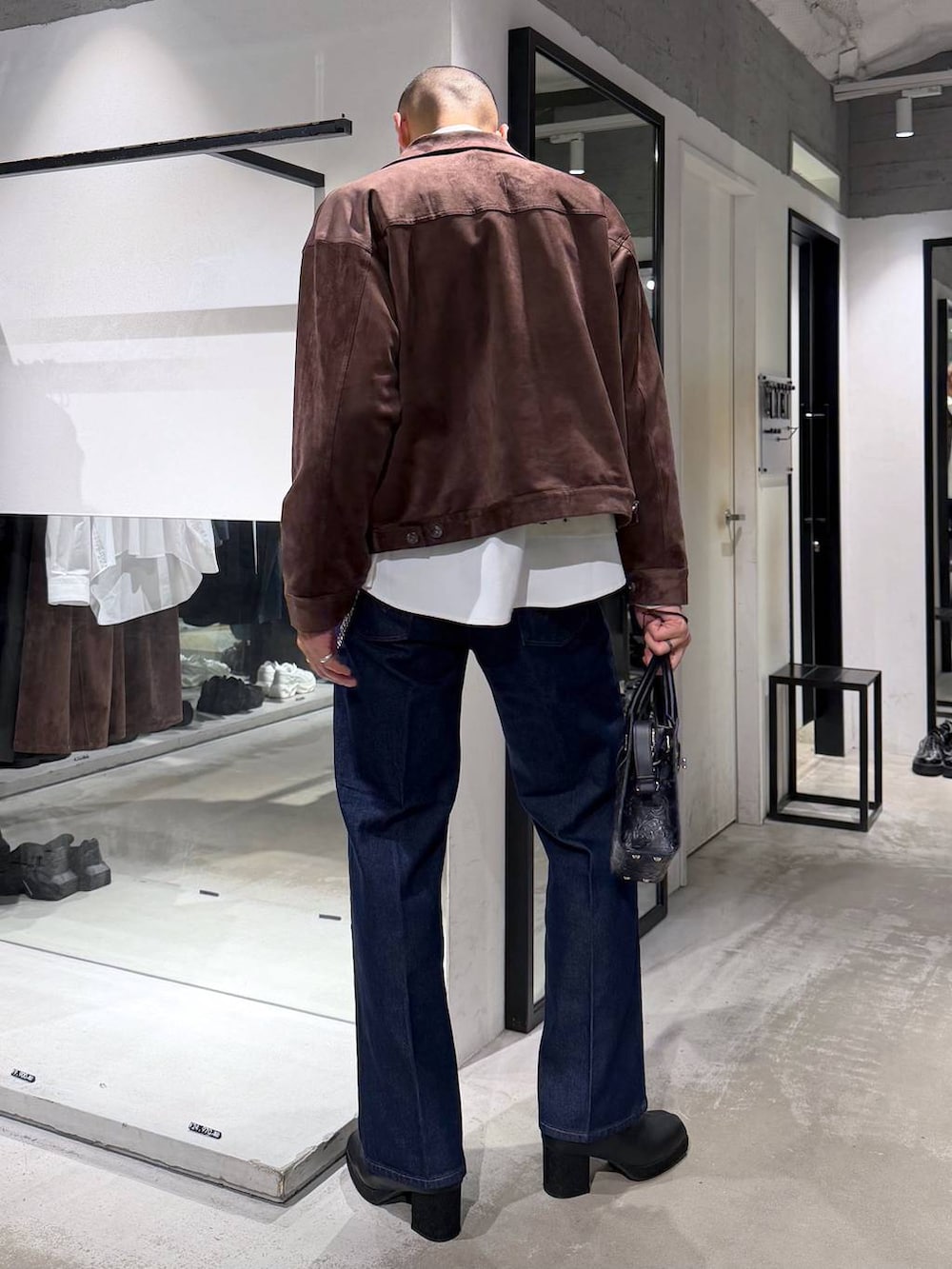 ブラック系のボストンバッグ、ブラック系のブーツ、ブルー系のデニムパンツを着用したメンズの秋コーディネートの3枚目の写真