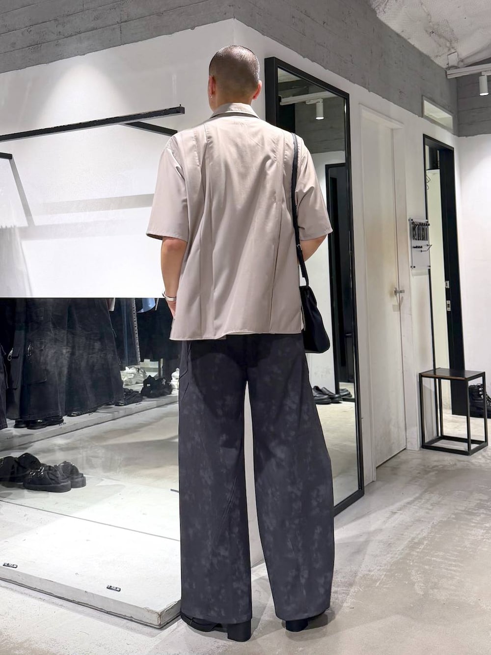 ブラック系のショルダーバッグ、ブラック系のサンダル、グレー系のスラックスを着用したメンズの夏コーディネートの3枚目の写真