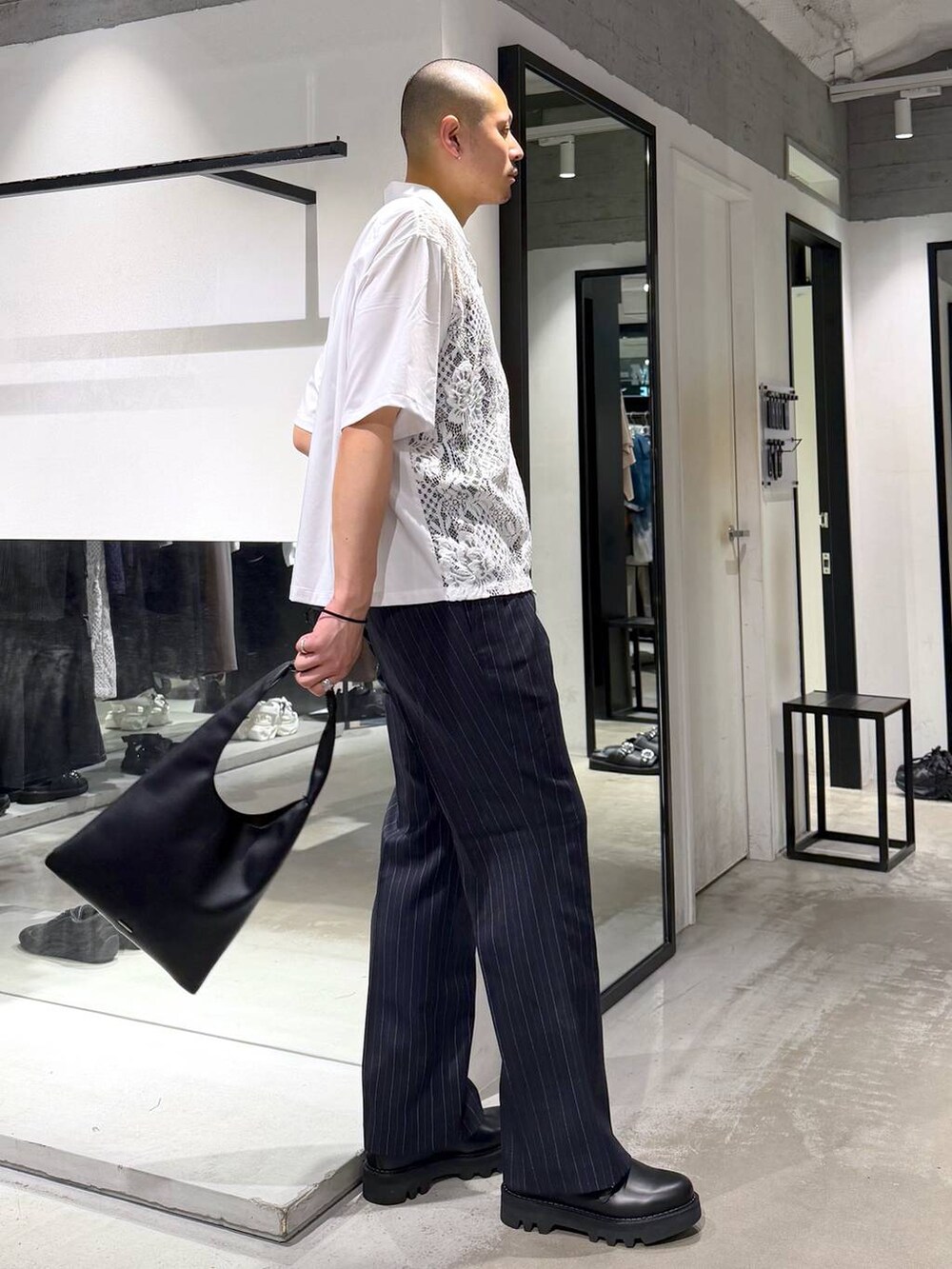 ブラック系のトートバッグ、ブルー系のスラックス、ブラック系のドレスシューズを着用したメンズの春コーディネートの4枚目の写真