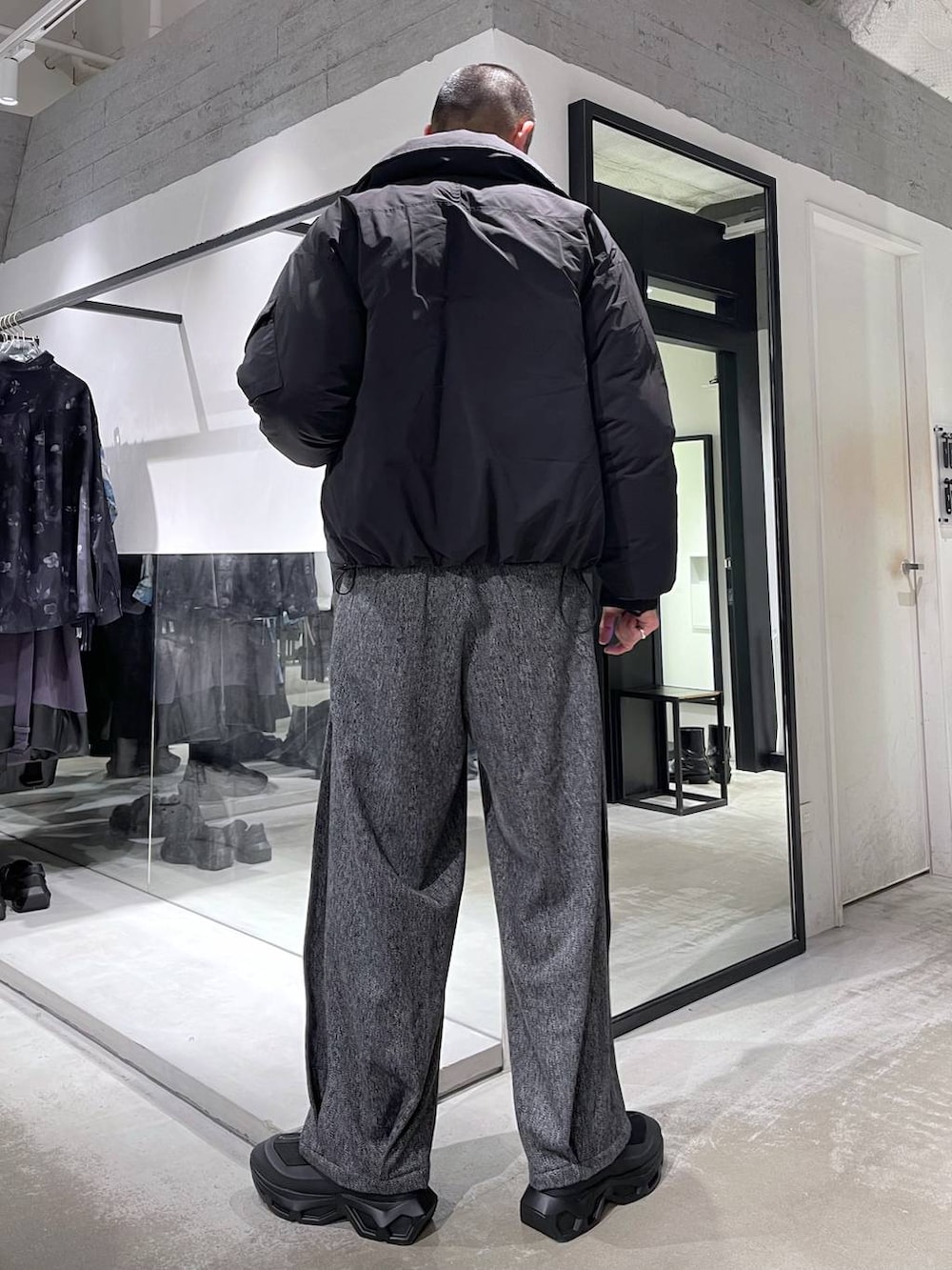 ブラック系のニット/セーター、ブラック系のダウンジャケット/コート、ブラック系のスラックスを着用したメンズの冬コーディネートの3枚目の写真