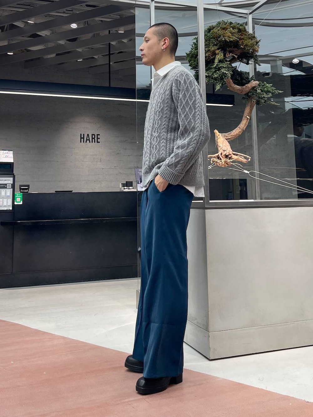 ブルー系のスラックス、ブラック系のショルダーバッグ、ブラック系のブーツを着用したメンズの秋コーディネートの2枚目の写真