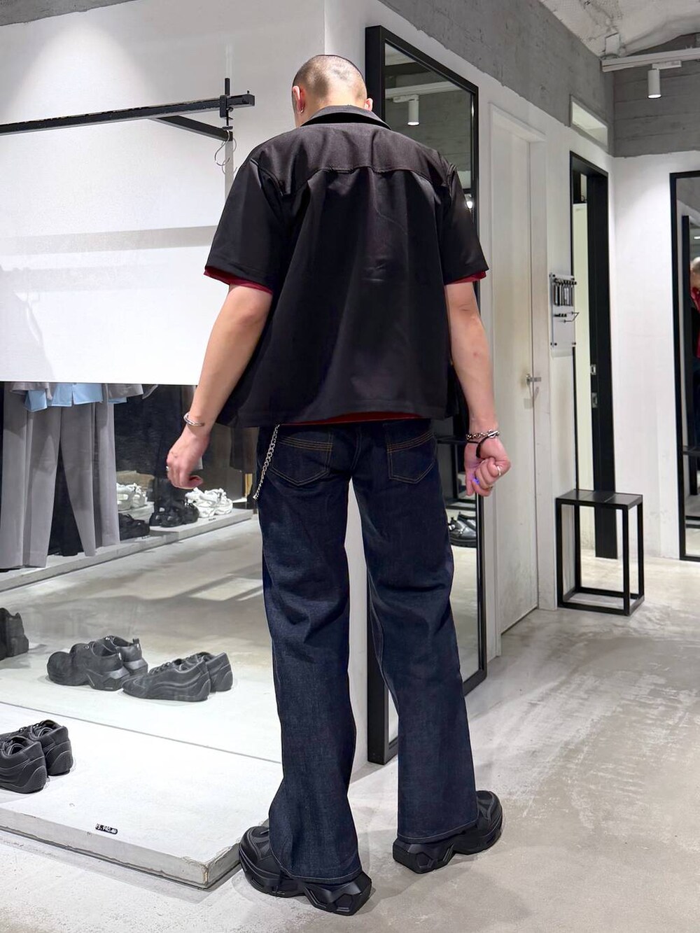 ブラック系のスニーカー、レッド系のTシャツ/カットソー、ブルー系のデニムパンツを着用したメンズの夏コーディネートの4枚目の写真