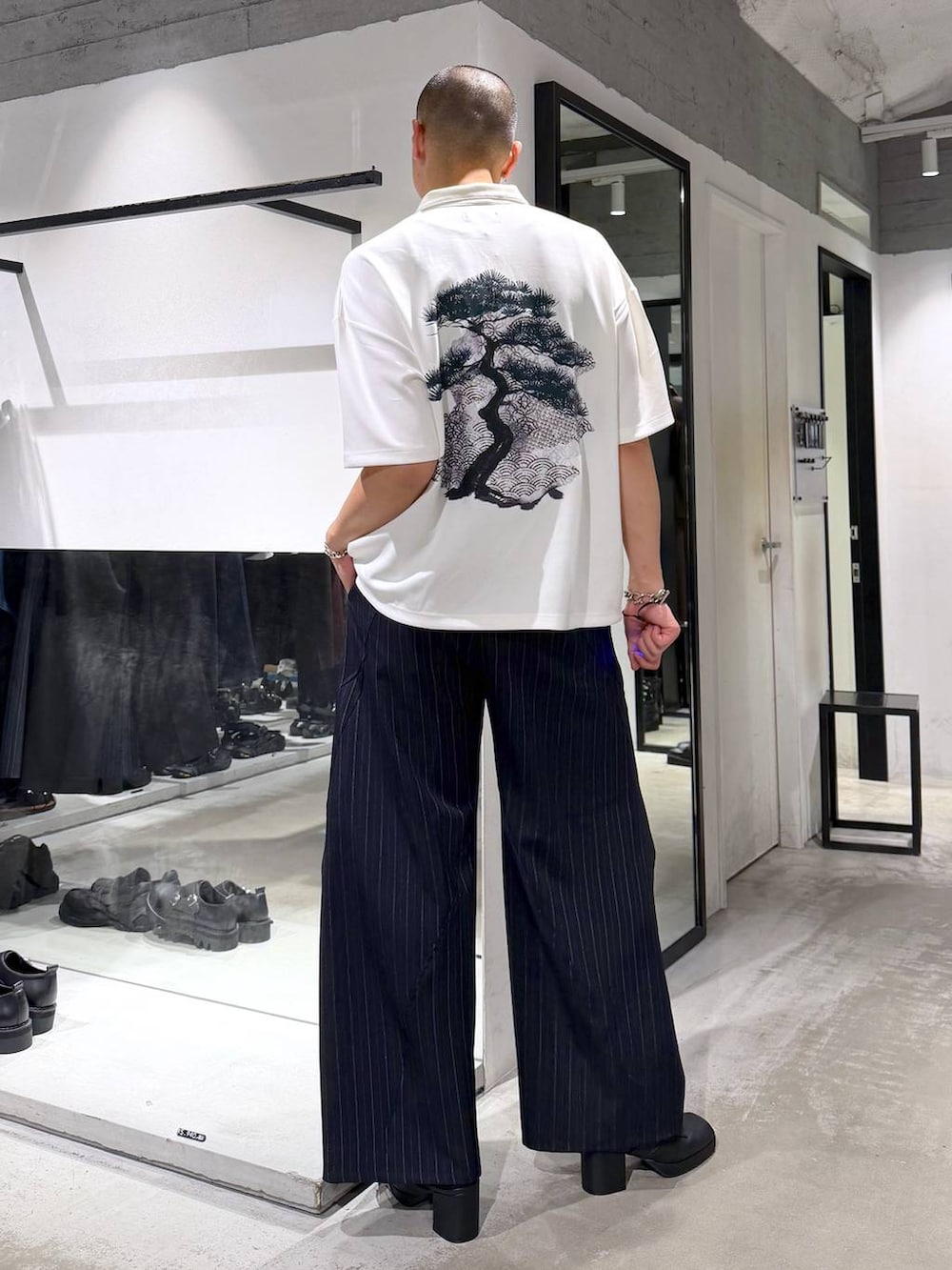 ホワイト系のTシャツ/カットソー、ブラック系のサンダル、ブルー系のスラックスを着用したメンズの夏コーディネートの3枚目の写真