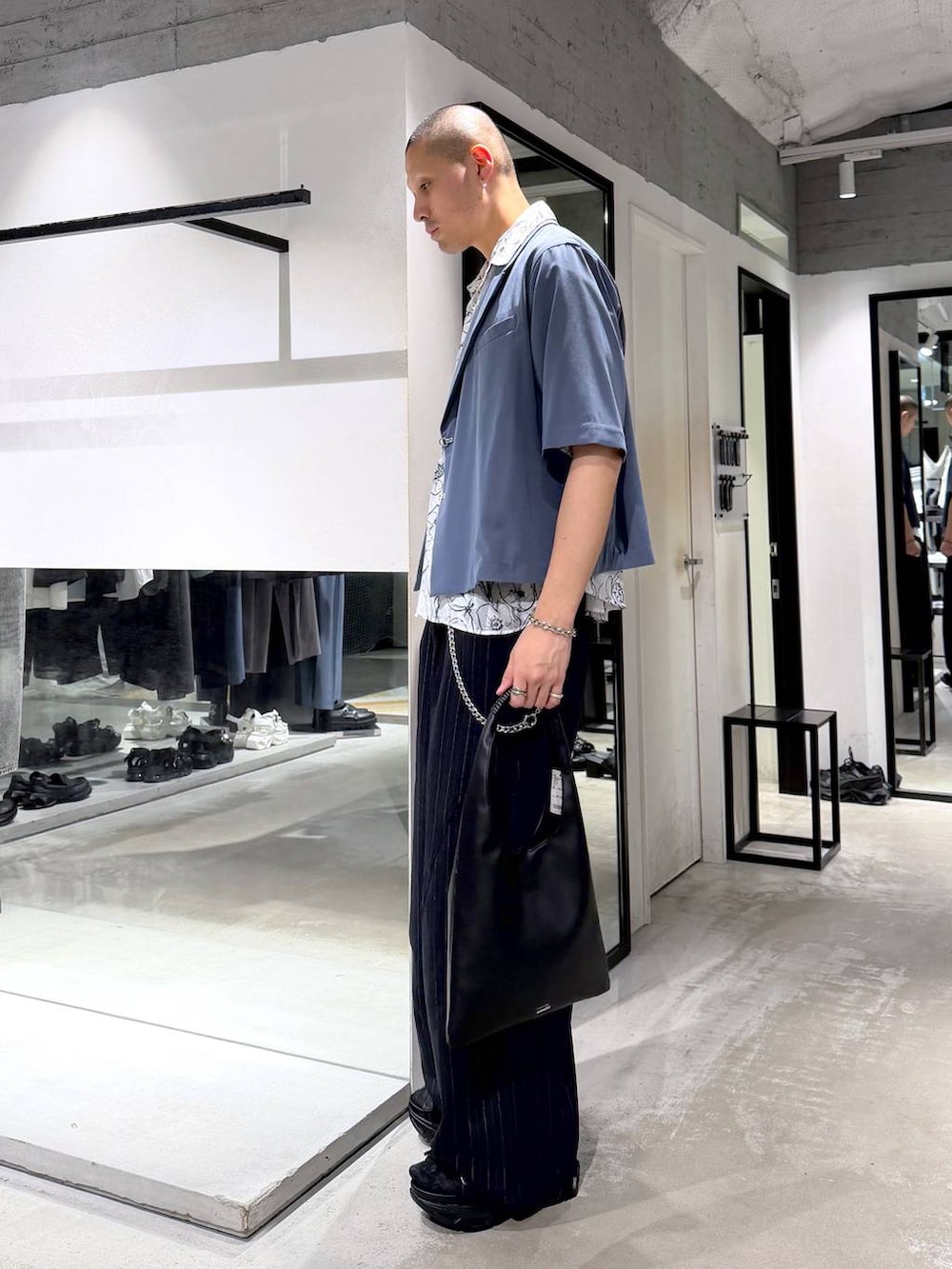 ブラック系のトートバッグ、ブラック系のサンダル、ブルー系のスラックスを着用したメンズの春コーディネートの3枚目の写真