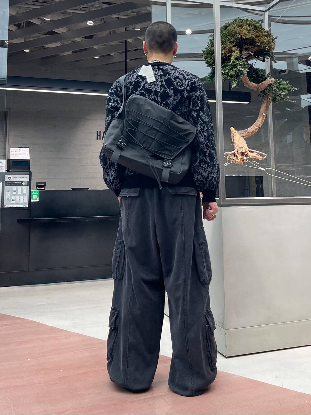 グレー系のニット/セーター、ブラック系のメッセンジャーバッグ、ブラック系のスウェットパンツを着用したメンズの秋コーディネートの3枚目の写真