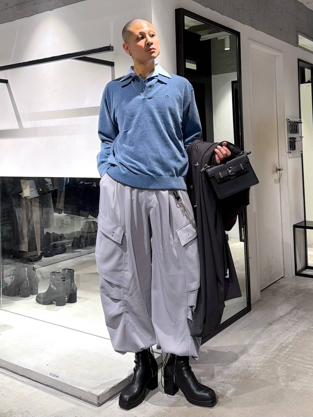 ブルー系のポロシャツ、ブラック系のブーツ、ブラック系のハンドバッグを着用したメンズの冬コーディネートの5枚目の写真