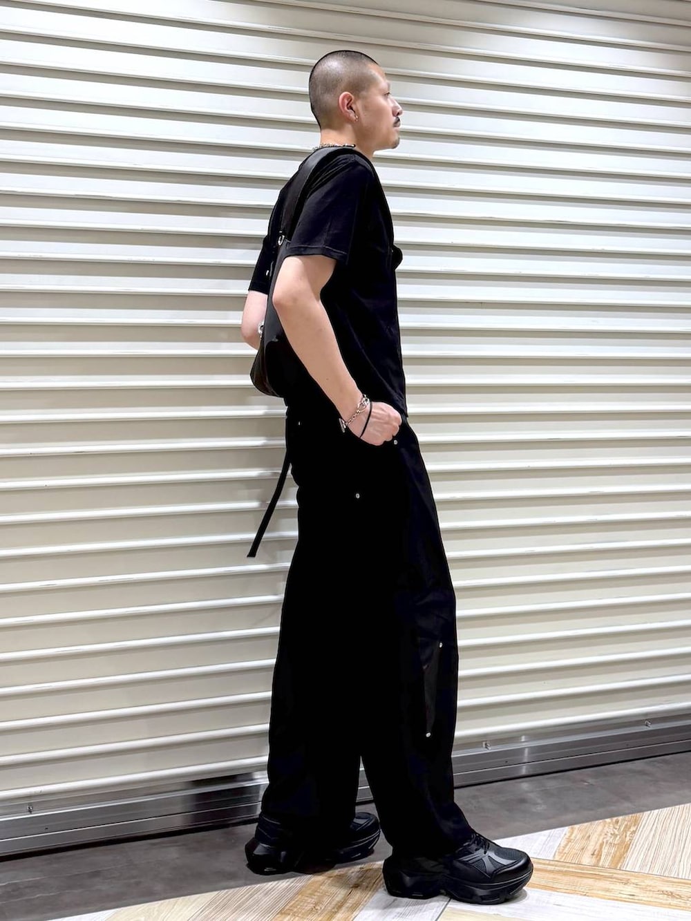 ブラック系のスラックス、ブラック系のTシャツ/カットソー、ブラック系のスニーカーを着用したメンズの夏コーディネートの4枚目の写真