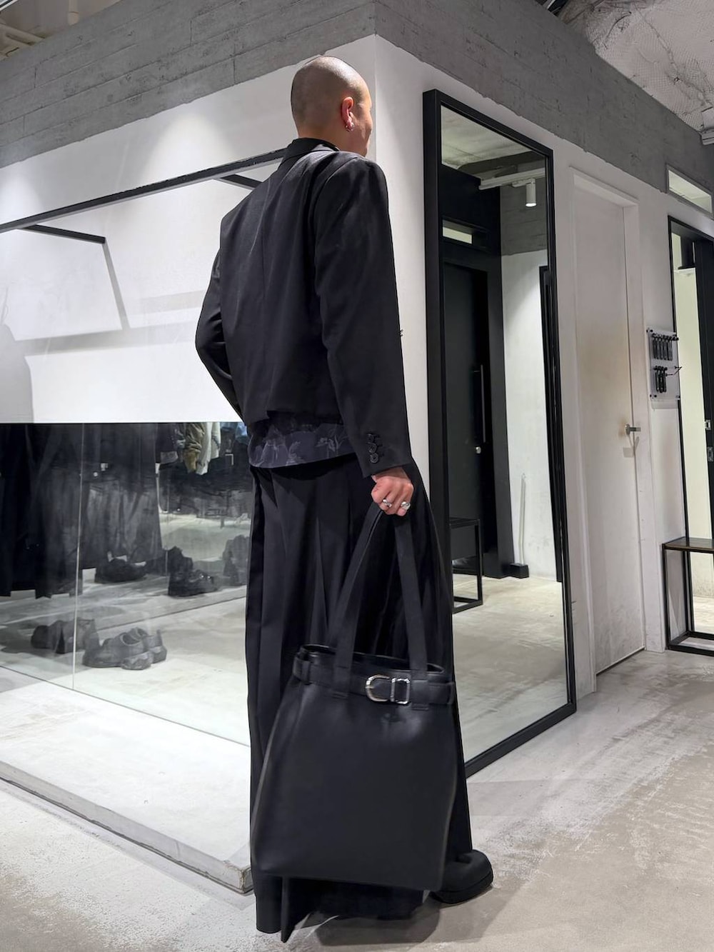 ブラック系のトートバッグ、ブラック系のその他パンツ、ブラック系のブーツを着用したメンズの冬コーディネートの4枚目の写真