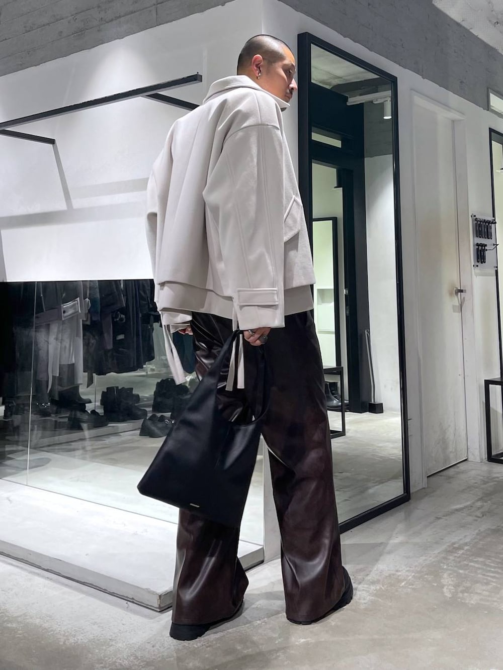 ブラック系のトートバッグ、ホワイト系のブルゾン、イエロー系のニット/セーターを着用したメンズの秋コーディネートの4枚目の写真