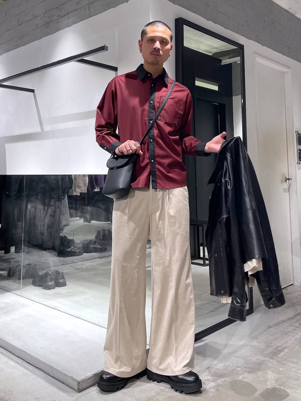 ベージュ系のスラックス、レッド系のシャツ/ブラウス、ブラック系のショルダーバッグを着用したメンズの冬コーディネートの5枚目の写真